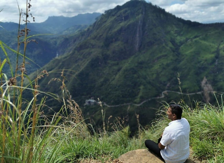 A person sitting on a rock overlooking a mountainous landscape. 1