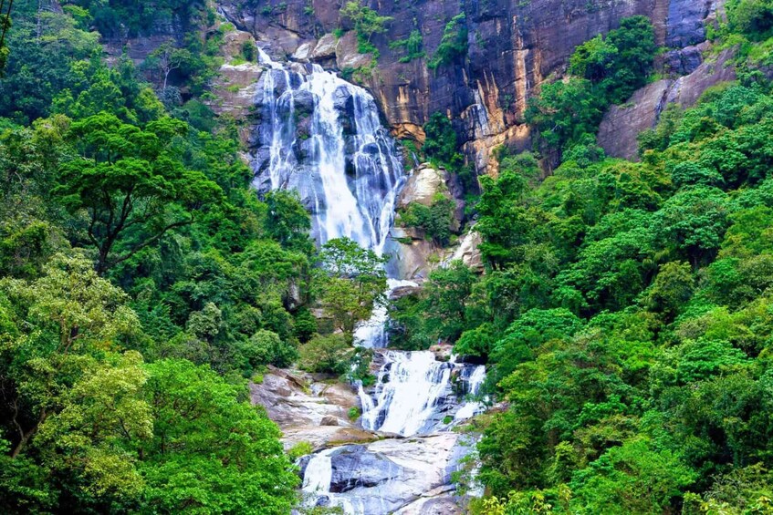 A multi-tiered waterfall surrounded by dense green forest. 2