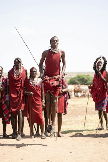 A group of people in traditional attire standing in a dry, open landscape. 3