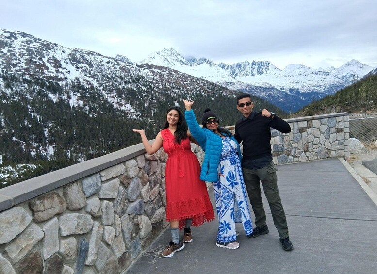 A group of people posing on a stone ledge with a mountainous landscape in the background. 5