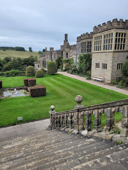 A castle with a well-manicured lawn, a pond, and stone steps leading up to the entrance. 4
