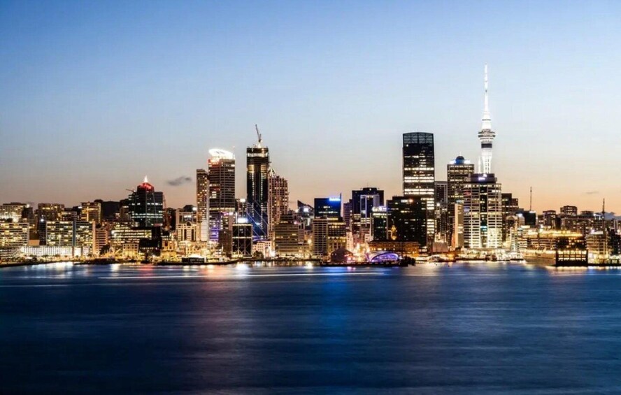 A city skyline at dusk with illuminated buildings and a prominent tower. 5