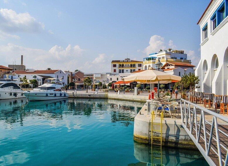 A marina with boats, a waterfront café, and buildings with Mediterranean architecture. 1