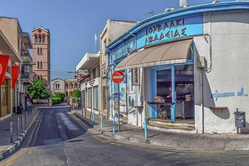 A street with a shop named 'SOYBAKI ABADIAE' and a church tower in the background. 2