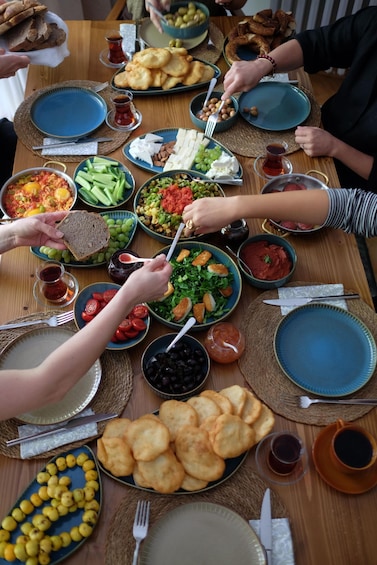 A group of people sharing a meal with various dishes and drinks on a wooden table. 3