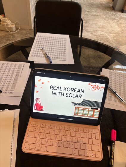 A laptop with a Korean language learning application open, a pen, and study materials on a table. 4