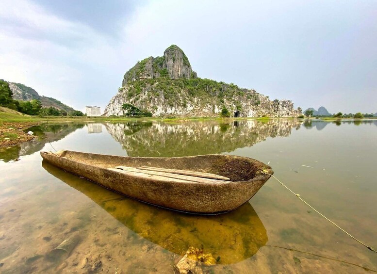 A traditional boat on calm water with a rocky island in the background. 1