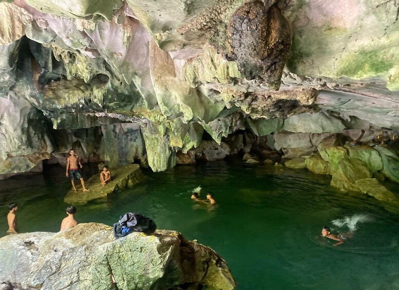 En hule med stalaktitter og stalagmitter, et vandbassin, samt folk der svømmer og står rundt omkring. 3