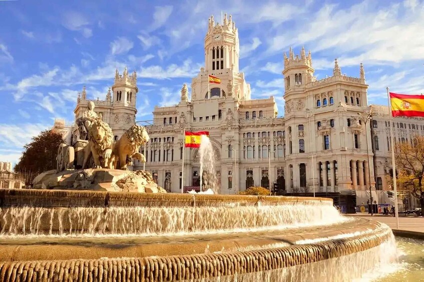 A grand building with a fountain in front, featuring lions and a flag. 5