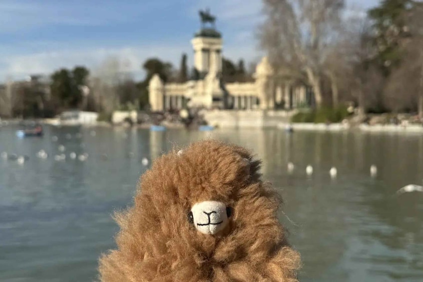 A stuffed animal in the foreground with a body of water and a building in the background. 1