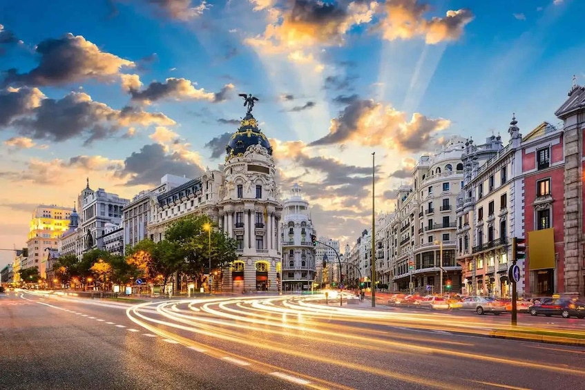 A city street with historic buildings, a prominent dome, and light trails from moving vehicles. 4