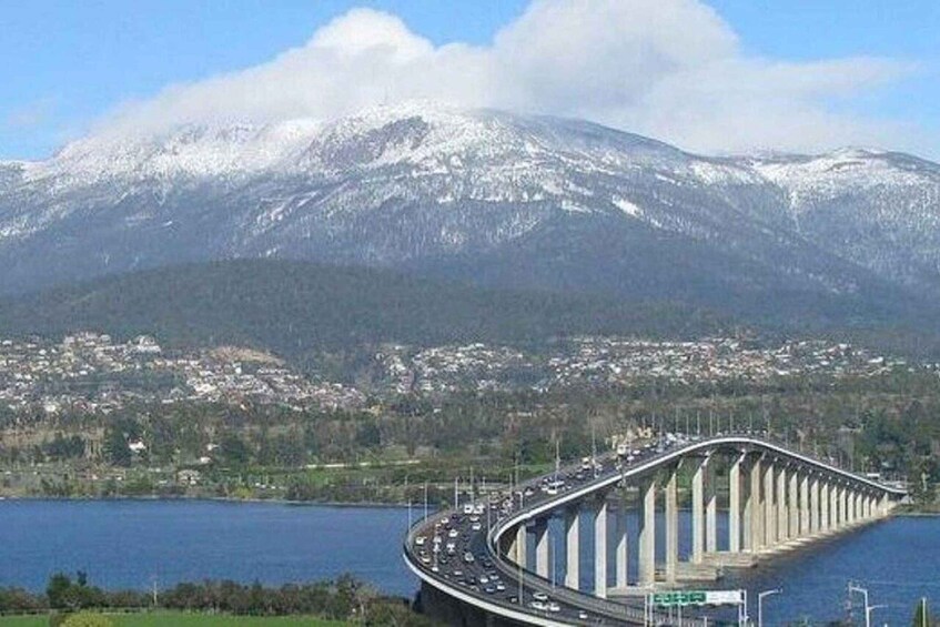 A curved bridge over a body of water with a snow-capped mountain in the background. 2