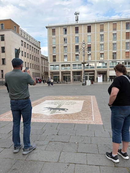 A man taking a photo, a woman standing, and a building with 'BNL' signage in the background. 2