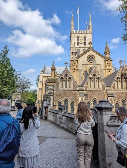 A historic church with a tall spire and clock tower, surrounded by visitors. 5