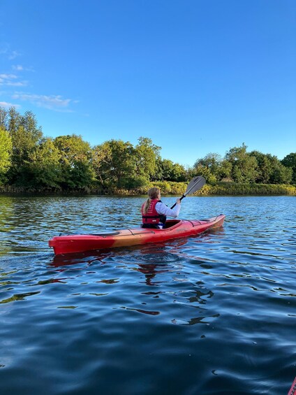 A person kayaking on a calm river surrounded by lush greenery. 5