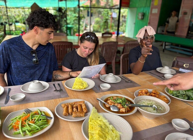 A group of people dining at an outdoor restaurant with various dishes on the table. 3