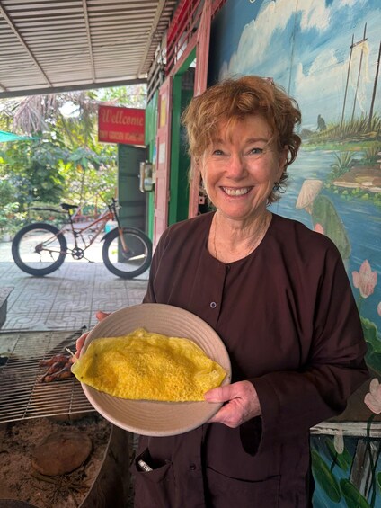 A person holding a bowl of food, a bicycle, and a mural with boats. 2
