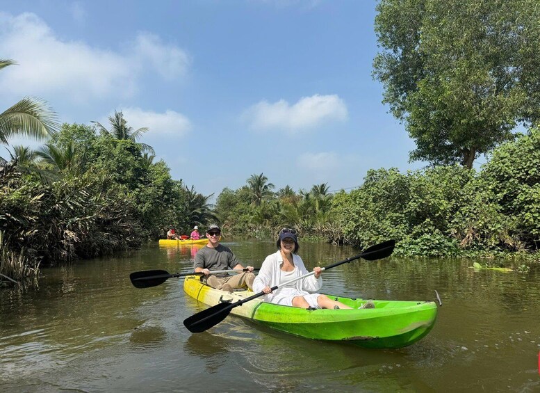 Two people kayaking on a river surrounded by dense vegetation. 4