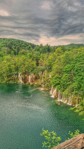 A serene lake surrounded by lush greenery and a forested hillside. 4