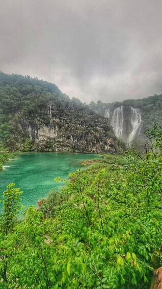 A waterfall cascading into a turquoise lake surrounded by lush greenery and rocky cliffs. 5