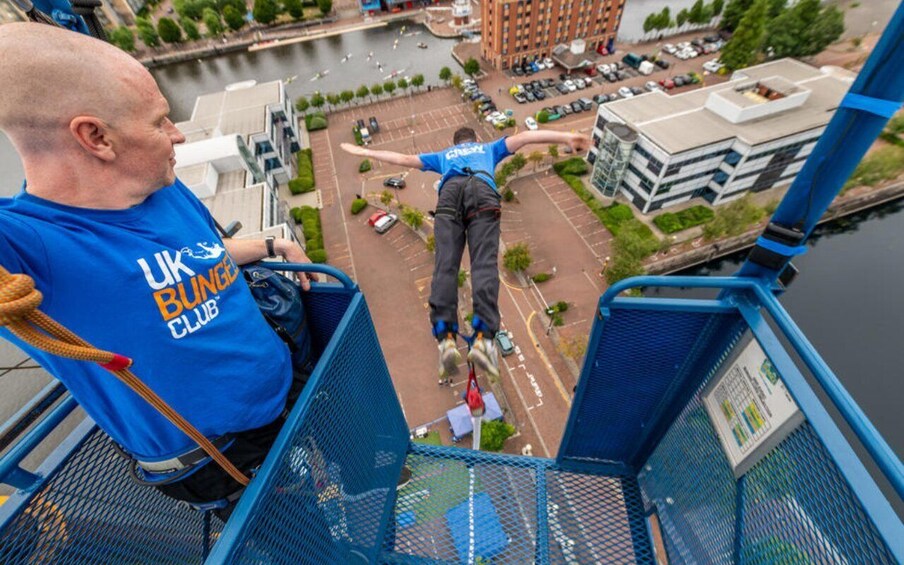 A person bungee jumping from a bridge with a cityscape in the background. 3