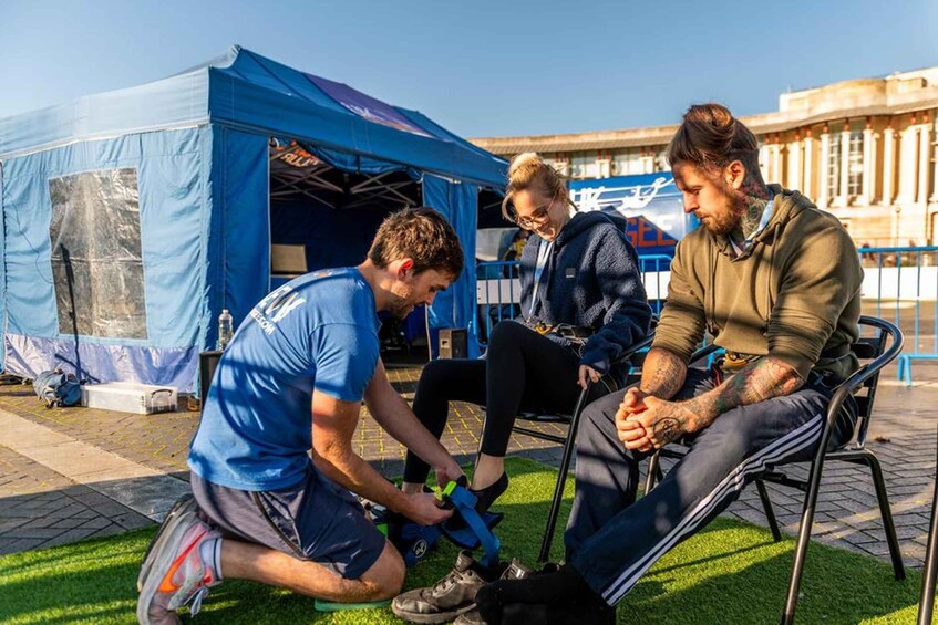A group of people sitting and standing outdoors near a blue tent. 2