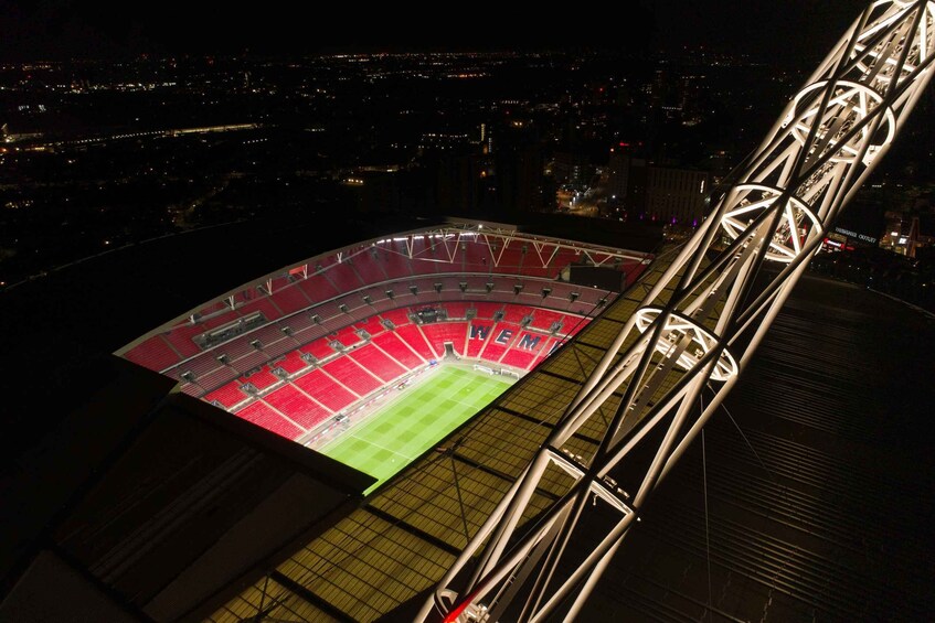 A stadium with a red field and seating, surrounded by a cityscape at night. 3