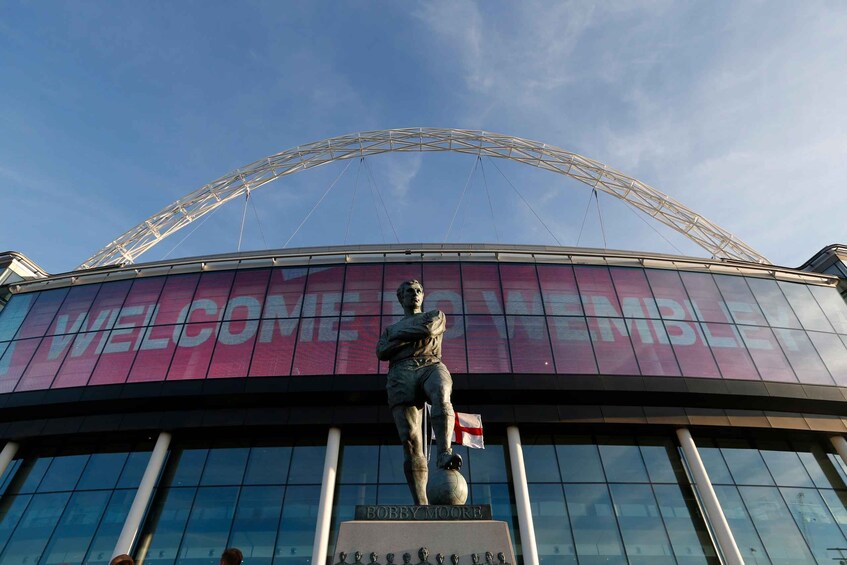 A stadium with a large 'WELCOME' sign and a statue of a football player. 1