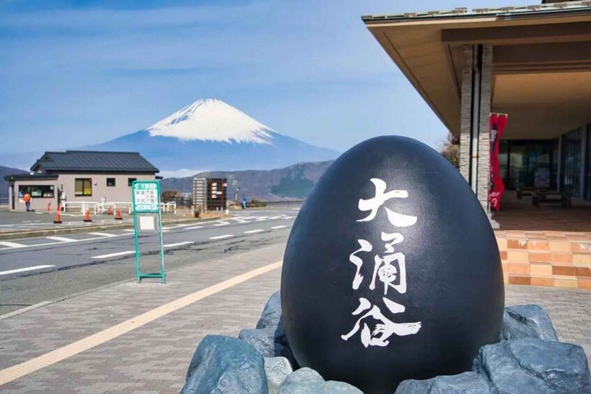 A large black sphere with Japanese characters, a road, a building, and a mountain in the background. 4