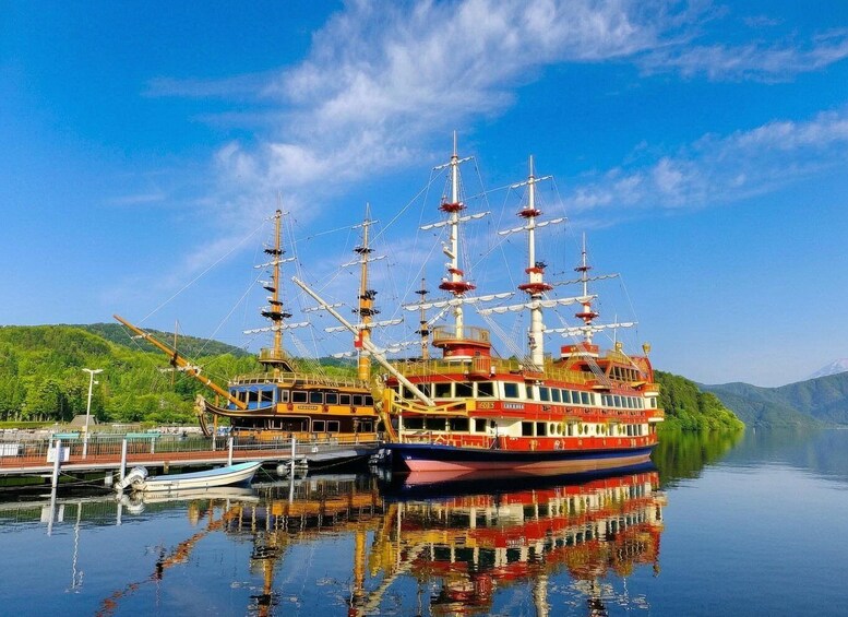 A tall ship docked at a pier with a mountainous backdrop. 3