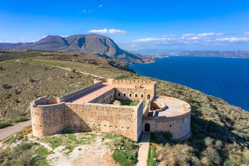 A coastal fortification with a surrounding landscape and a mountain in the background. 1