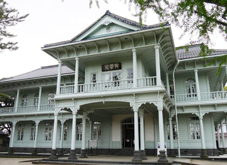 A large, light green colonial-style building with multiple balconies and columns. 4