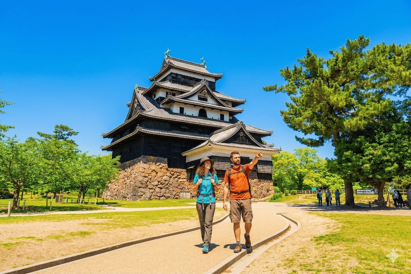 A couple walking on a path with a traditional Japanese castle in the background. 1