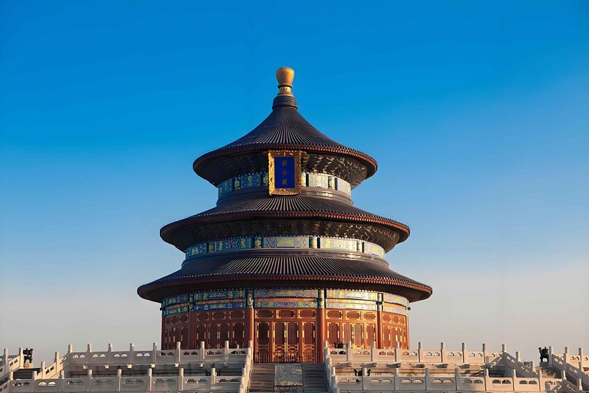 A traditional Chinese pavilion with a multi-tiered roof, intricate blue and gold decorations, and a clear blue sky in the background. 4