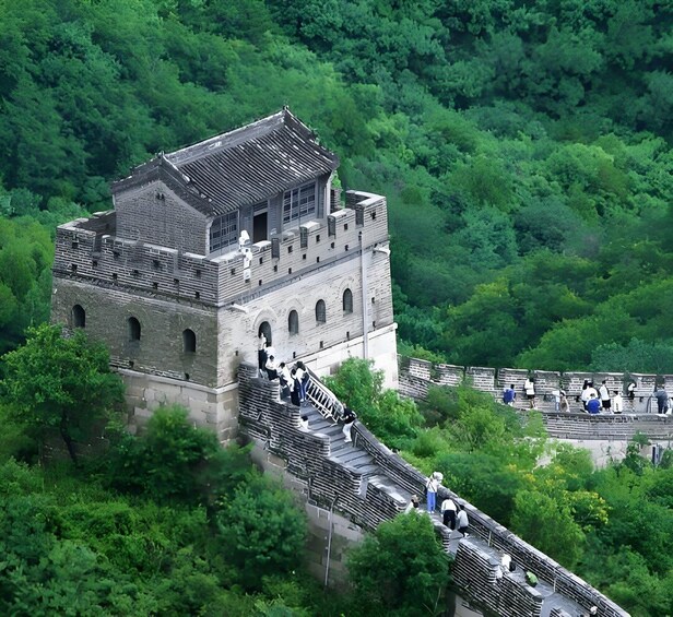 A historic stone structure with a tiled roof, surrounded by lush green forest. 2