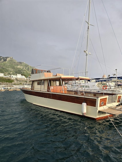 A wooden boat docked at a marina with a mountainous backdrop. 4