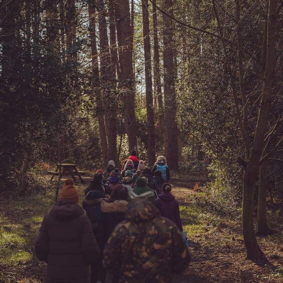 A group of people gathered in a forest, facing a speaker. 3