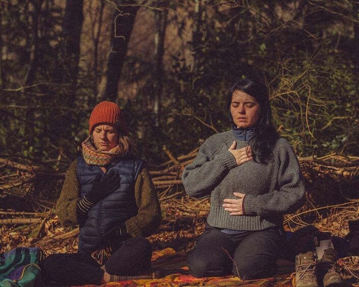 Two people sitting on a blanket in a forest. 2