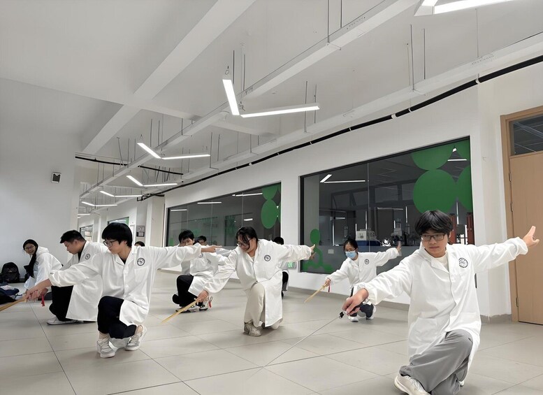 A group of people in white uniforms practicing martial arts in a modern indoor space with geometric ceiling lights and green wall decorations. 3