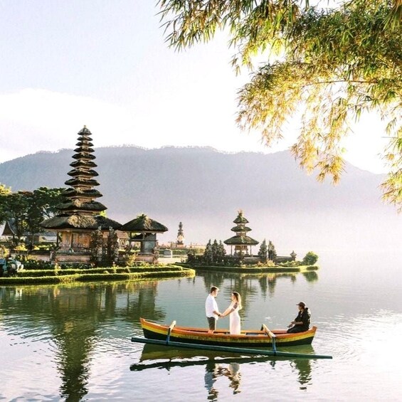 A calm lake with a traditional boat, a pagoda, and a temple in the background. 1