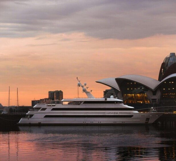 A large yacht docked near a modern opera house at sunset. 2