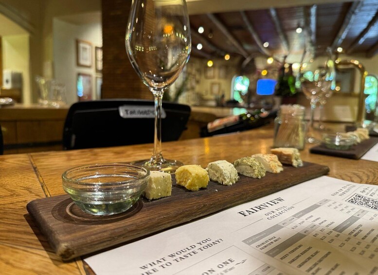 Ein Restaurantambiente mit Speisekarte, einem Weinglas und einer Auswahl an Käse auf einer Holzplatte. 2