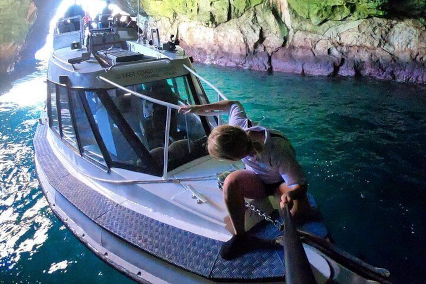 A boat with a person sitting on the edge, surrounded by clear blue water and rocky cliffs. 1