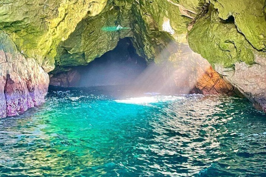 Une grotte avec une eau turquoise cristalline et des formations rocheuses verdoyantes. 1