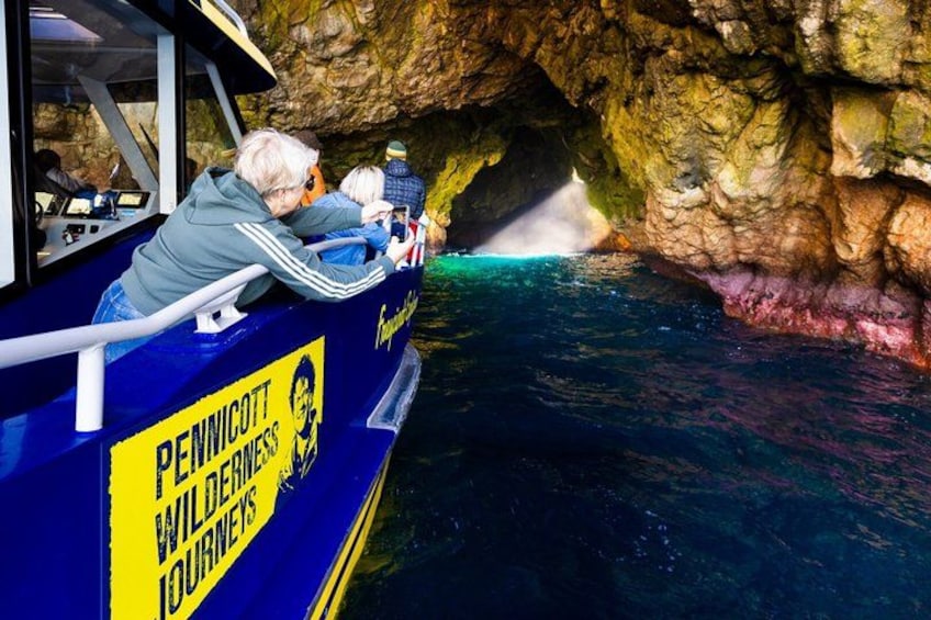 A boat with people on board, a rocky cave entrance, and water. 3