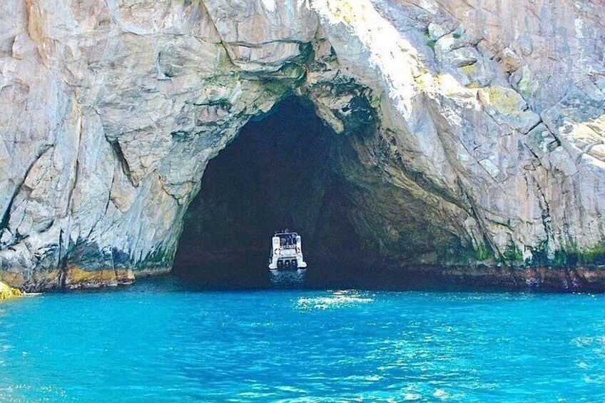 A boat entering a natural rock arch formation surrounded by turquoise water. 5