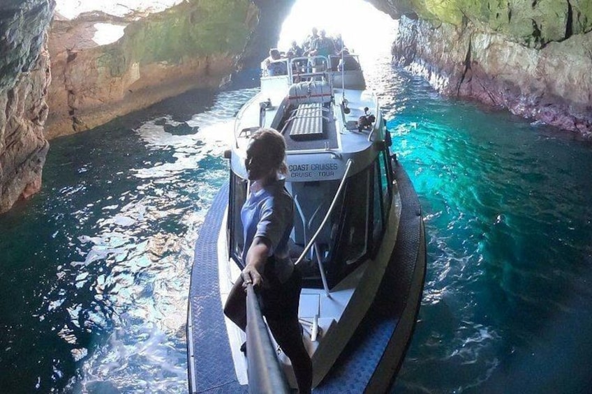 A boat with a person steering, surrounded by clear blue water and rocky cliffs. 2
