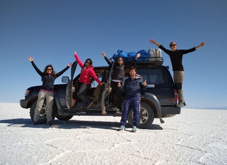 Un grupo de personas posando con un vehículo en un paisaje nevado. 1