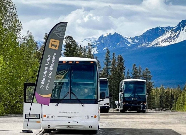 A bus with a flag, parked in a parking lot with mountains in the background. 3