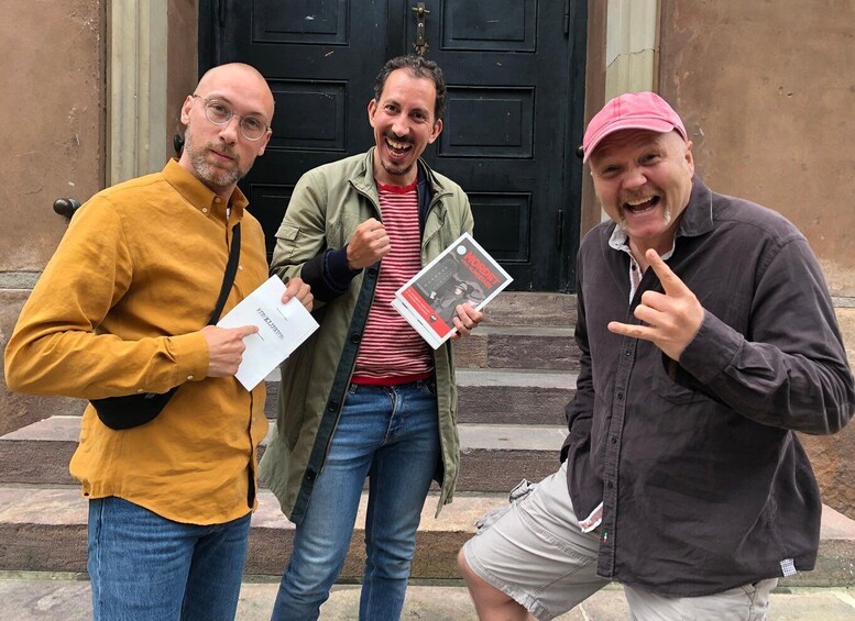 Three people standing in front of a black door, holding books. 4